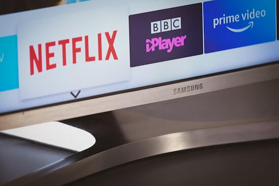 A photograph of a TV screen showing the logos of Netflix, BBC iPlayer, and Amazon Prime Video.